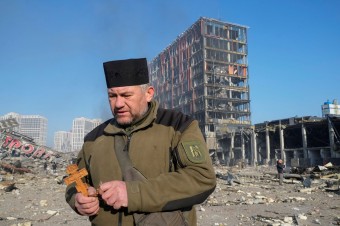 Fotovýber: Kňaz sa modlí na mieste zbombardovaného obchodného domu v Kyjeve. (AP